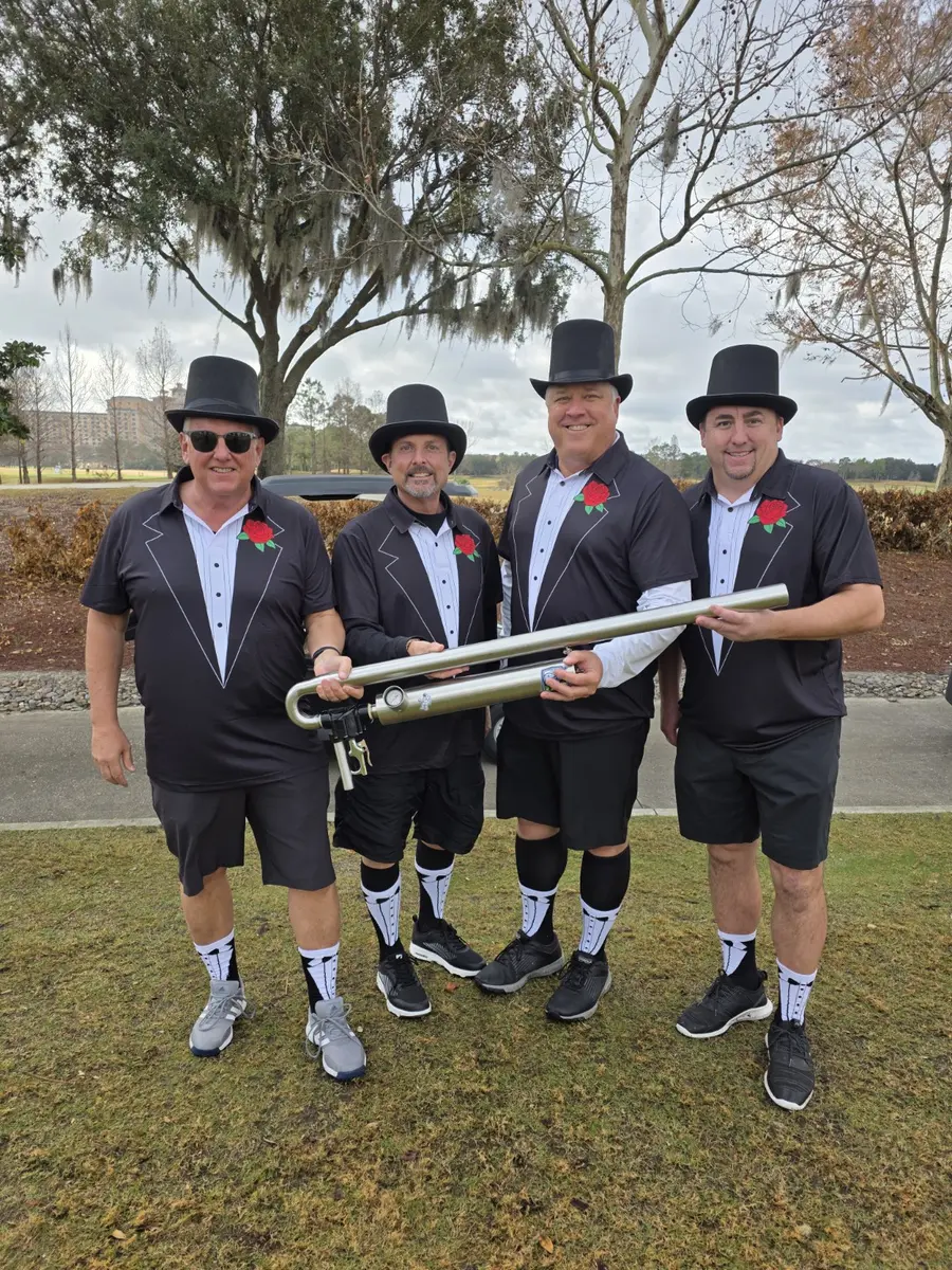 Golfers in tuxedo outfits holding a golf ball launcher